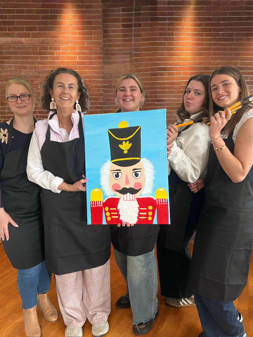 ladies holding a painting of the nutcracker and smiling